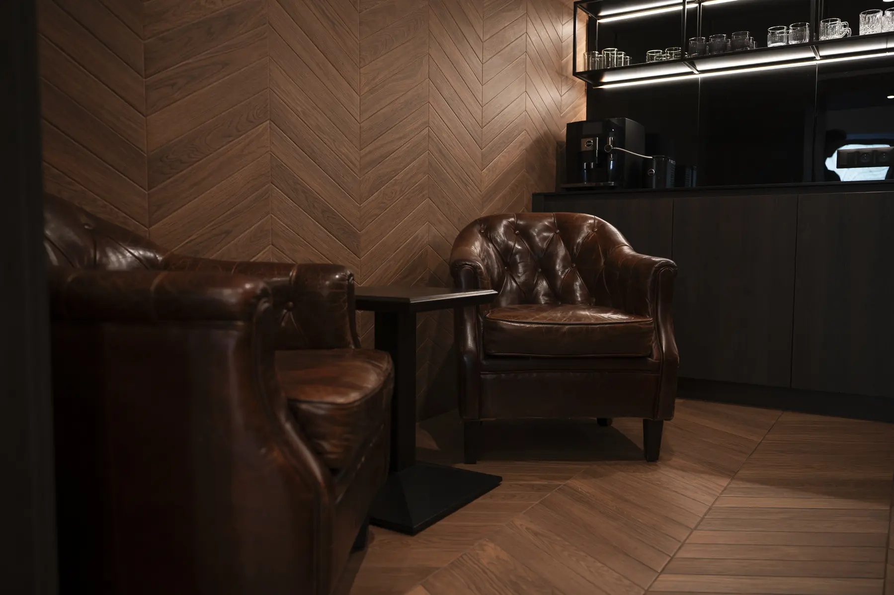 Lounge s koženými křesly a dřevěným obkladem v rybí kosti